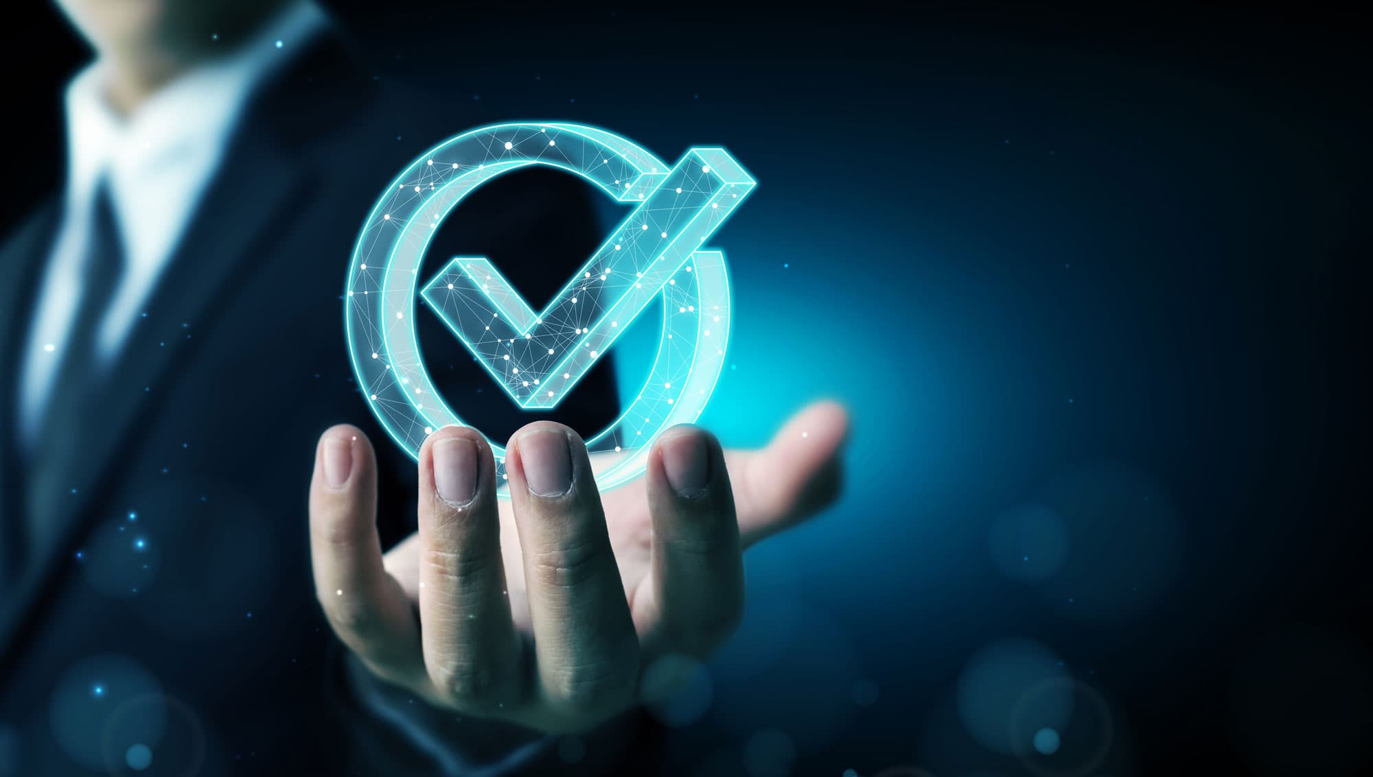 Eine Hand hält ein leuchtendes, digitales Häkchen-Symbol vor einem dunklen, futuristischen Hintergrund.